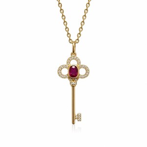 Puede incluir: Un collar de oro con un colgante en forma de llave. La cabeza de la llave tiene un diseño de cuatrifolio incrustado con pequeños diamantes blancos y centrado con un rubí rojo intenso de talla ovalada. El vástago y el paletón tienen diamantes.