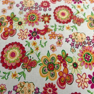May include: A white fabric with a colorful floral pattern. The design includes red, pink, orange, and yellow flowers, green leaves, butterflies, birds, and sheep. The overall theme is a cheerful, whimsical design.