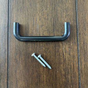 May include: Black plastic cabinet handle with two silver screws.