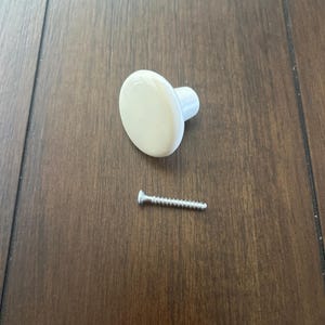 May include: White ceramic knob with a round top and a short, cylindrical base. A silver screw is included.