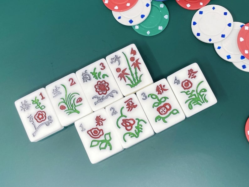 May include: Nine white tiles with red and green floral designs and numbers 1, 2, 3, and 4. The tiles are arranged in a staggered pattern on a green surface.