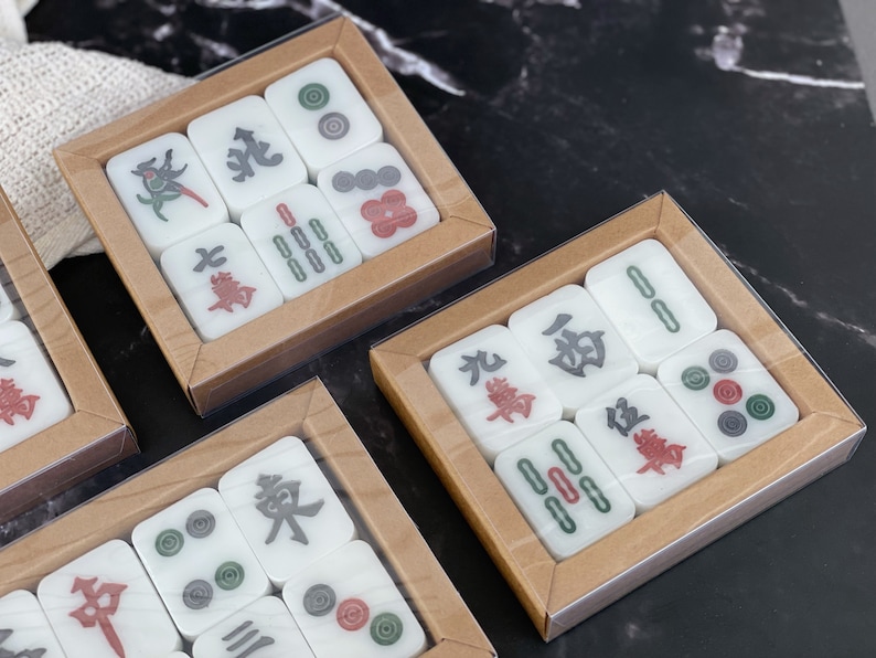 May include: Three sets of mahjong tiles in wooden boxes. Each set contains 14 tiles with various Chinese characters and symbols. The tiles are white with black and red accents.