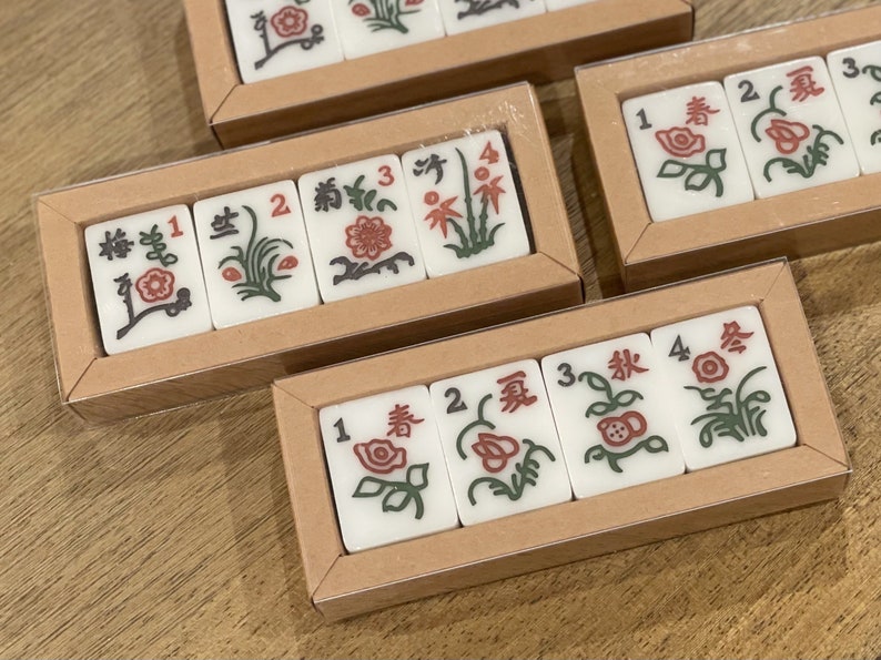 May include: Four sets of Chinese dominoes in wooden boxes. Each domino has a number 1 through 4 and a different floral design. The designs include a red flower, a green plant, a red flower with green leaves, and a green plant with a red flower.