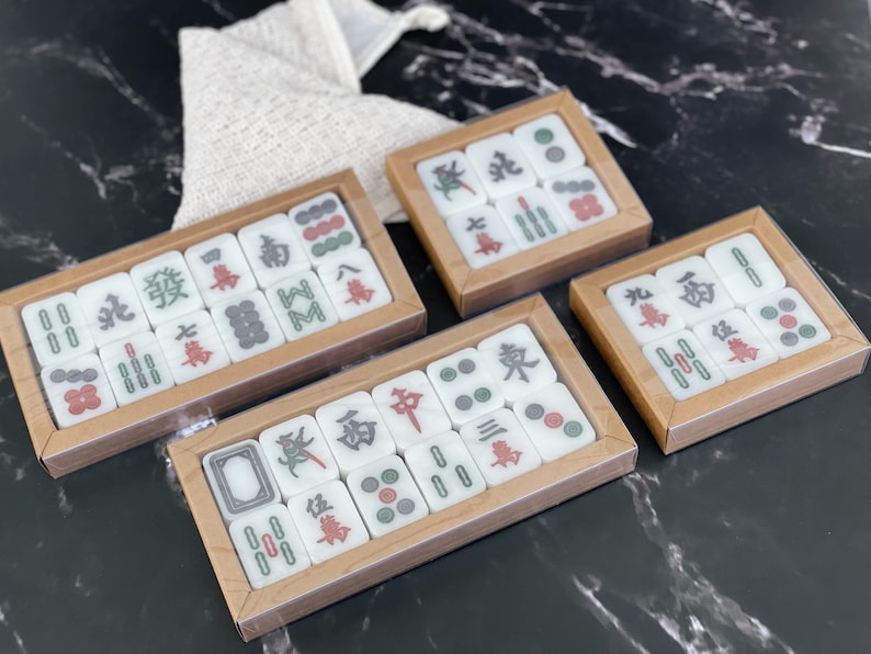 May include: Four sets of white mahjong tiles in wooden boxes. Each set contains 14 tiles with Chinese characters and symbols. The tiles are arranged in a grid pattern within the boxes.