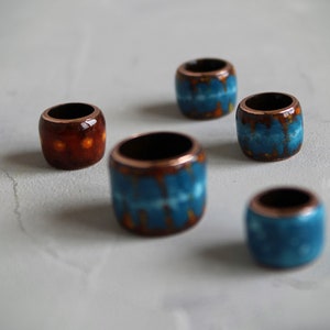 May include: Five ceramic beads with copper accents. The beads are decorated with blue and orange patterns.