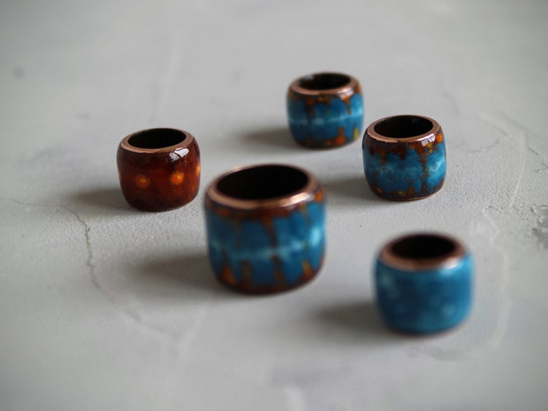 May include: Five ceramic beads with copper accents. The beads are decorated with blue and orange patterns.