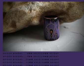 May include: A set of five purple and black ceramic beads with a spider design. The beads are different sizes, with hole sizes ranging from 4mm to 15mm. The beads are 16mm to 25mm in height.