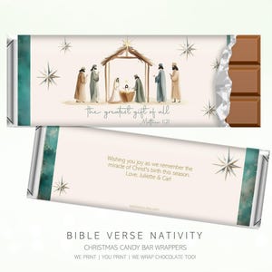 May include: Chocolate bar wrapper with a Nativity scene illustration. The wrapper features a teal and white design with text that reads "the greatest gift of all" and "Matthew 1:21". The back of the wrapper has a message wishing joy for the Christmas season.