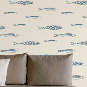May include: Wallpaper featuring a repeating pattern of blue fish on a cream background. Some fish have a solid line design while others feature a cross-hatched pattern. The bottom right corner displays a small white logo with the text MARIE LE MOAL.