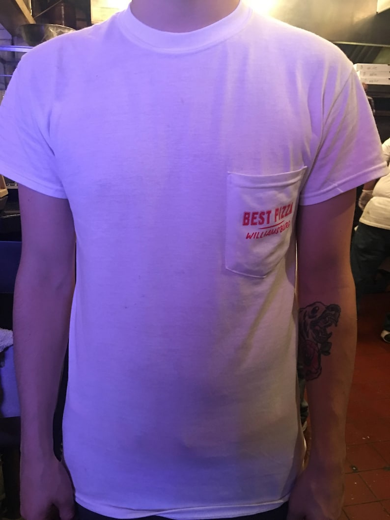 May include: White t-shirt with a red pocket that says "Best Pizza Williamsburg" in red text.