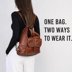 Peut inclure: Un sac à dos en cuir marron avec des bretelles fines et une poche frontale à rabat. Le texte sur la droite indique : ONE BAG. TWO WAYS TO WEAR IT. Le sac présente un compartiment principal structuré et une poche extérieure avec boucle.