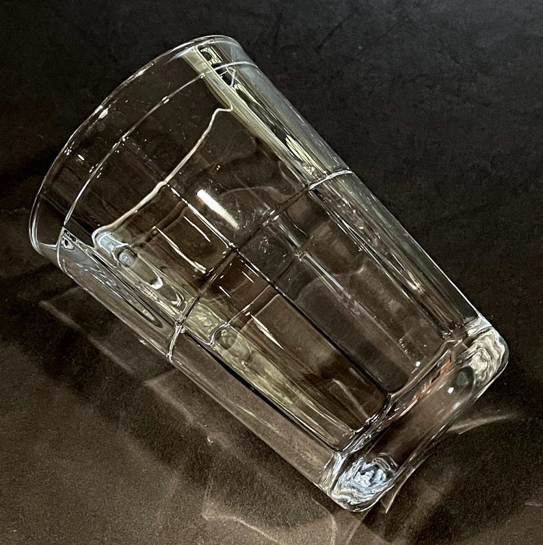 May include: A clear, rectangular glass with a grid pattern. The glass is empty and angled, showcasing its design. The glass is made of clear glass and is suitable for beverages.