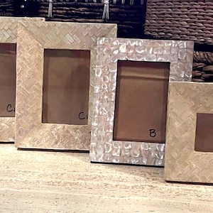 May include: Four decorative photo frames with textured, off-white surfaces. The frames vary in size and shape, with rectangular and square options. The frames have a neutral color palette and are suitable for various home decor styles.