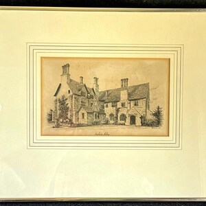 Puede incluir: Dibujo arquitectónico en tonos sepia enmarcado de un gran edificio con múltiples chimeneas, ventanas y una fachada detallada. La obra de arte está enmarcada en un marco de color plateado.