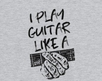 May include: A gray t-shirt with the text "I play guitar like a" and a black and white illustration of a hand playing a guitar.