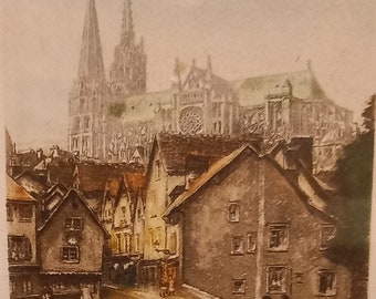 May include: A vintage postcard depicting a street scene in Chartres, France. The postcard shows a narrow street lined with old buildings, with the iconic Chartres Cathedral in the background. The street is cobblestone and there are people walking on it. The postcard is titled "Chartres - Rue du Bourg et Pont Bouju" and has a handwritten signature in the bottom right corner.