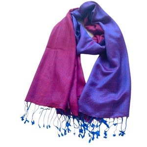 May include: A purple and blue ombre scarf with blue fringe. The scarf is made of a soft, silky material.