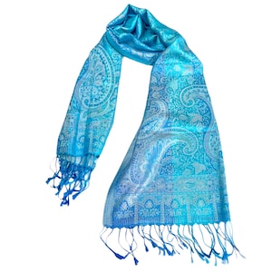 May include: A blue paisley patterned scarf with fringed edges. The scarf is made of a soft, silky material.