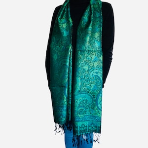 May include: A green paisley patterned scarf with a fringed edge. The scarf is made of a soft, silky material.