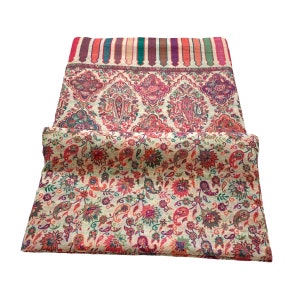 May include: A cream-colored shawl with a paisley pattern in shades of red, pink, green, and blue. The shawl has a multi-colored border with stripes of red, orange, yellow, green, blue, and purple.