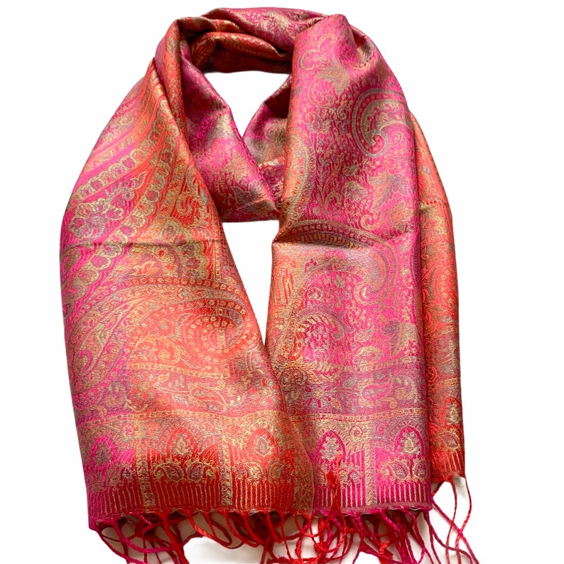 May include: A pink and gold paisley patterned scarf with fringed edges.