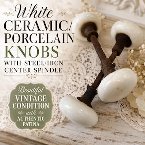 May include: Two white ceramic or porcelain knobs with a rusted steel or iron center spindle. The text on the image reads: White CERAMIC/PORCELAIN KNOBS WITH STEEL/IRON CENTER SPINDLE, Beautiful VINTAGE CONDITION with AUTHENTIC PATINA.