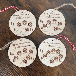 May include: Four wooden Christmas ornaments with the text "chance made us neighbors, hearts made us friends." Each ornament features a neighborhood map with house illustrations and the year 2021. They have twine and red and white string for hanging.
