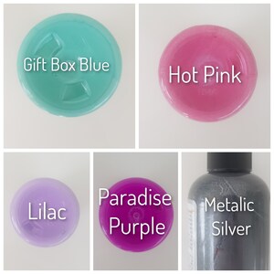 May include: Five bottles of paint in different colors: lilac, hot pink, gift box blue, paradise purple, and metallic silver.