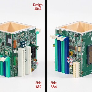 Puede incluir: Un contenedor cuadrado de madera con los lados cubiertos por placas de circuito impreso verdes que presentan varios componentes electr&oacute;nicos, incluyendo ranuras RAM azules y blancas, un z&oacute;calo de CPU y conectores. El texto Design 1044 es visible.