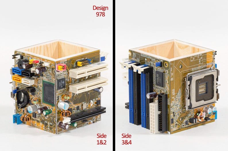Peut inclure: Un porte-stylo carr&eacute; fabriqu&eacute; &agrave; partir de panneaux de carte m&egrave;re d'ordinateur recycl&eacute;s. L'ext&eacute;rieur pr&eacute;sente des circuits imprim&eacute;s dor&eacute;s avec divers composants &eacute;lectroniques, dont des fentes blanches et bleues, des condensateurs et un support de processeur. Le texte indique Design 978.