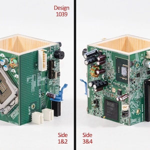 Puede incluir: Un contenedor cuadrado con paredes interiores de madera clara y paneles exteriores hechos de placas de circuito impreso verdes. Las placas presentan componentes electr&oacute;nicos que incluyen condensadores, un z&oacute;calo de CPU y un chip Intel.