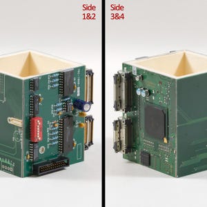 Peut inclure: Un r&eacute;cipient carr&eacute; fabriqu&eacute; &agrave; partir de circuits imprim&eacute;s verts avec des composants &eacute;lectroniques tels que des condensateurs, des circuits int&eacute;gr&eacute;s et des connecteurs fix&eacute;s &agrave; l'ext&eacute;rieur. Le texte Design 559, Side 1&2 et Side 3&4 est visible.