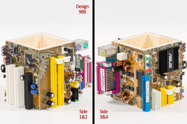 Peut inclure: Un porte-stylo carr&eacute; fabriqu&eacute; &agrave; partir de panneaux de cartes m&egrave;res d'ordinateur recycl&eacute;s. L'ext&eacute;rieur pr&eacute;sente des circuits imprim&eacute;s bruns avec des fentes jaunes, blanches et noires, des condensateurs et divers ports. Le texte indique Design 988.