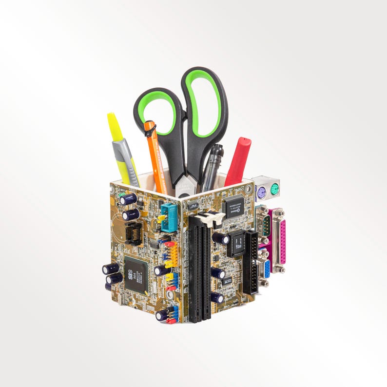 Peut inclure: Un organisateur de bureau carr&eacute; fabriqu&eacute; &agrave; partir de cartes de circuits imprim&eacute;s recycl&eacute;es, dot&eacute; de divers composants &eacute;lectroniques, ports et fentes. Le r&eacute;cipient contient une paire de ciseaux noirs et verts, un surligneur jaune et deux stylos.