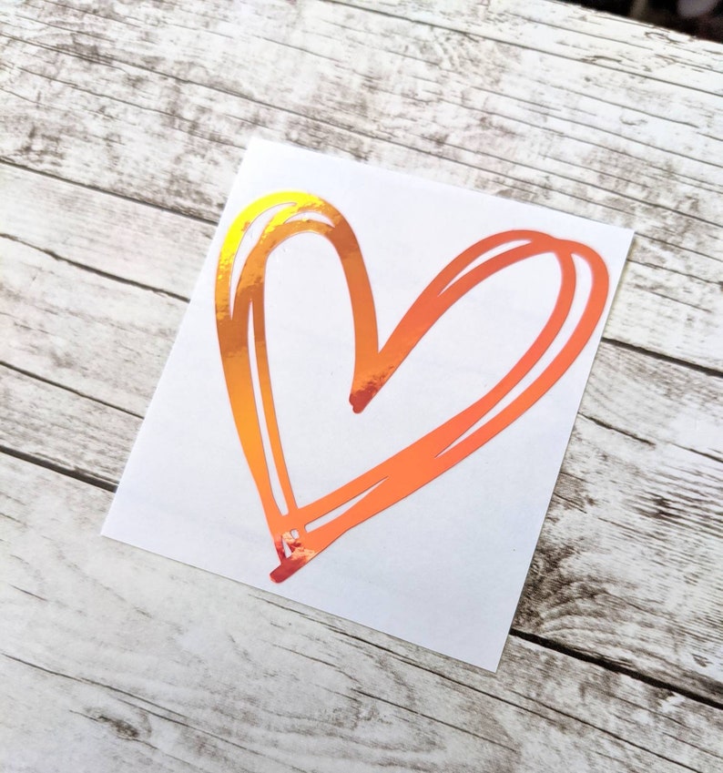 May include: A sticker of a heart drawn in a simple, hand-drawn style. The heart is a vibrant orange color with a holographic finish.