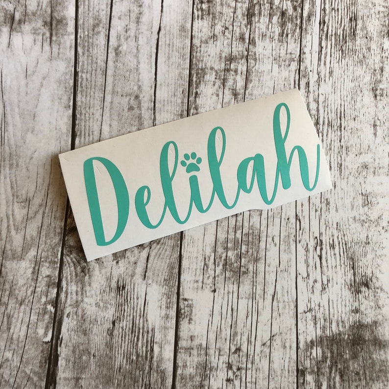 May include: Teal vinyl decal with the name "Delilah" and a paw print in cursive lettering.