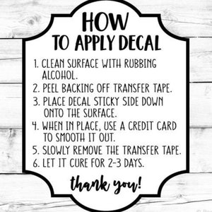 May include: Black and white text on a white background with a black border. The text reads "HOW TO APPLY DECAL" and includes six steps for applying a decal. The steps include cleaning the surface with rubbing alcohol, peeling the backing off the transfer tape, placing the decal sticky side down onto the surface, using a credit card to smooth it out, slowly removing the transfer tape, and letting it cure for 2-3 days. The text also includes "thank you!"
