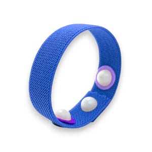 May include: A blue elastic wristband with two white and purple button closures. The band is made of a textured fabric and is designed to be worn around the wrist. The wristband is a vibrant blue color.