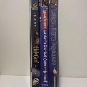 Może przedstawiać: Kolekcja trzech film&oacute;w DVD Monty Pythona w kartonowym pudełku. Tytuły to "Monty Python and the Holy Grail", "And Now for Something Completely Different" i "Life of Brian". Pudełka są w r&oacute;żnych odcieniach niebieskiego i czarnego.