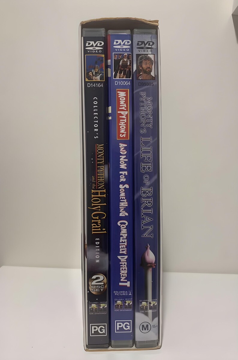 Może przedstawiać: Kolekcja trzech film&oacute;w DVD Monty Pythona w kartonowym pudełku. Tytuły to "Monty Python and the Holy Grail", "And Now for Something Completely Different" i "Life of Brian". Pudełka są w r&oacute;żnych odcieniach niebieskiego i czarnego.