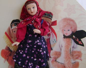 May include: Three Russian nesting dolls, or matryoshka dolls, in traditional folk costumes. The largest doll is wearing a red headscarf, a red and black dress with a floral pattern, and a red and black skirt. The middle doll is wearing a blue and white headscarf and a blue and white dress. The smallest doll is wearing a white fur coat and a white hat.