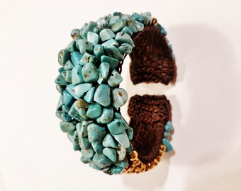 May include: A turquoise stone bracelet with a brown woven band. The bracelet is made of many small, irregular shaped turquoise stones.