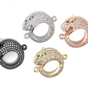 Könnte beinhalten: Vier silberne, goldene, roségoldene und schwarze panthershaped Verschlüsse mit klaren Kristall-Akzenten und grünen Augenakzenten.