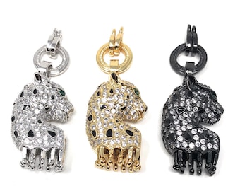 May include: Three silver, gold, and black leopard charm pendants with clear and black rhinestones and green eyes.