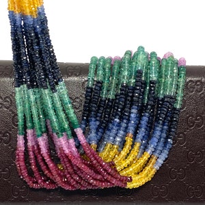 May include: A multi-colored strand of gemstone beads. The beads are arranged in rows of yellow, blue, green, and red. The beads are faceted and have a polished finish.