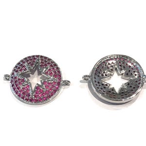 Pu&ograve; includere: Due ciondoli in metallo color argento con un ritaglio a forma di stella al centro. I ciondoli sono decorati con strass rosa.