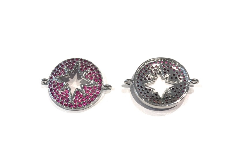 Pu&ograve; includere: Due ciondoli in metallo color argento con un ritaglio a forma di stella al centro. I ciondoli sono decorati con strass rosa.