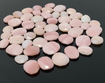 May include: A collection of pink opal cabochons, each with a unique pattern and shape. The stones are smooth and polished, with a soft, milky pink hue.