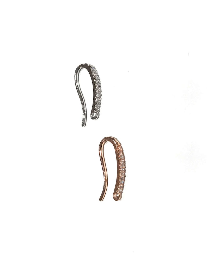 May include: Two jewelry clasps, one silver and one rose gold, with clear crystal accents.