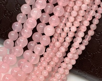 Può includere: Fili di perline di quarzo rosa di varie dimensioni. Le perline sono di un colore rosa tenue e hanno una superficie liscia e lucida. Le perline sono infilate, pronte per la creazione di gioielli.